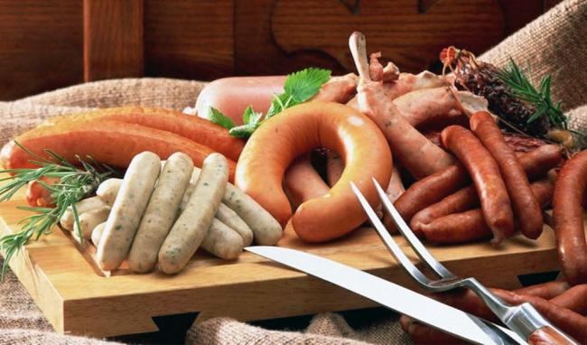 Ассорти из сырых колбас и сосисок  На деревянной доске лежит ассорти из сырых колбас и сосисок