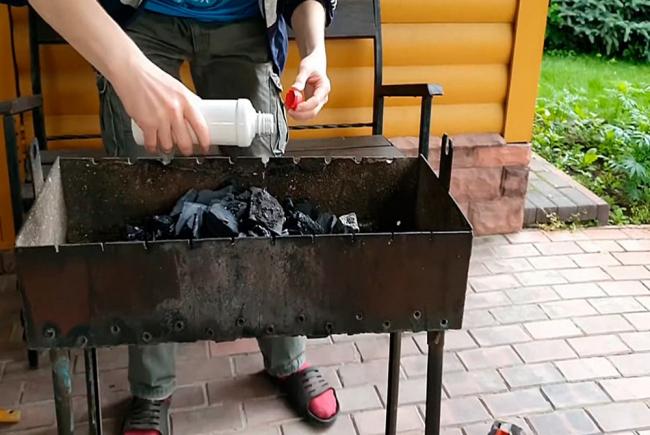 Использование геля для розжига Мужчина использует гель для розжига огня