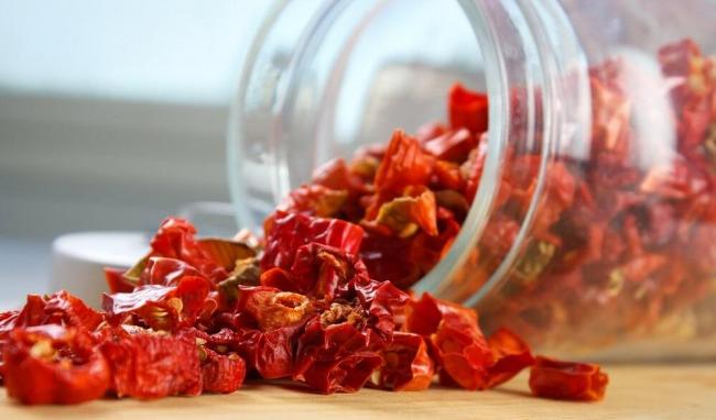 Чили, высушенный кусочками Кусочки сушеного чили рассыпаны из банки