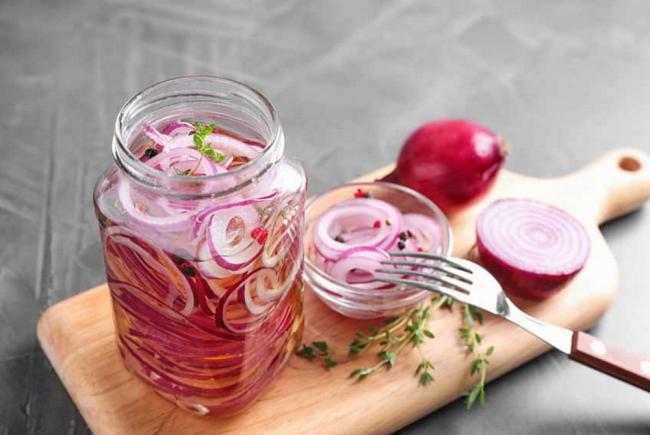 Маринованный лук в банке На деревянной доске маринованный лук в банке