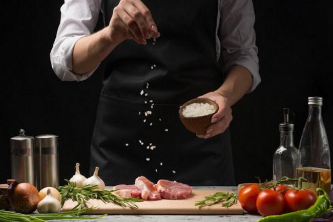 Повар солит мясо перед приготовлением  Повар солит мясо