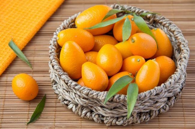 Спелые плоды кумквата Свежий кумкват в плетеной корзине