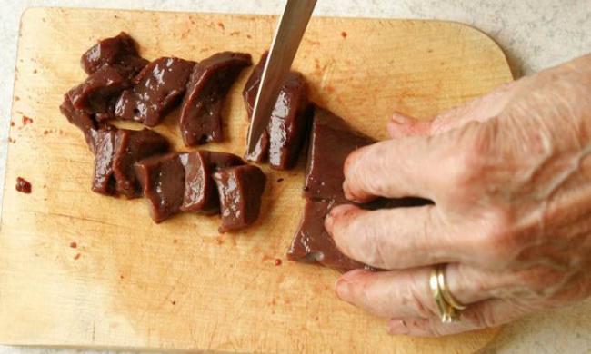 Нарезание свиной печени на кусочки Свиная печень и нож