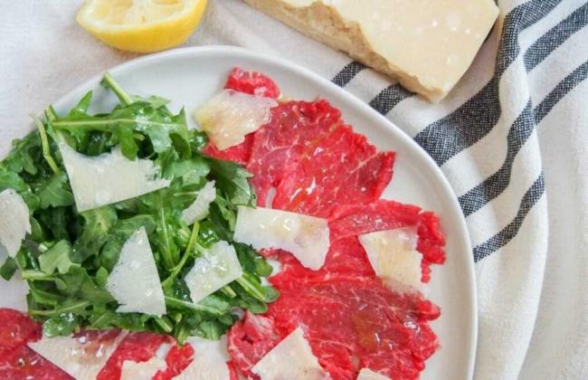 Блюдо из вяленого мяса, зелени и сыра Тонко нарезанное мясо с зеленью и сыром