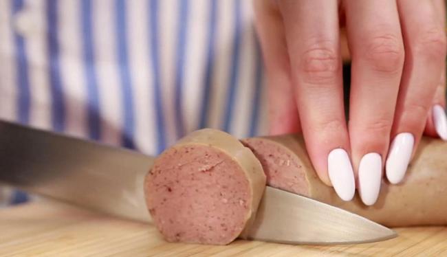 Употребление колбасы из ливера Женщина режет ливерную колбасу